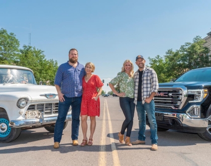 Four people standing by trucks