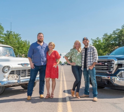 Four people standing by trucks